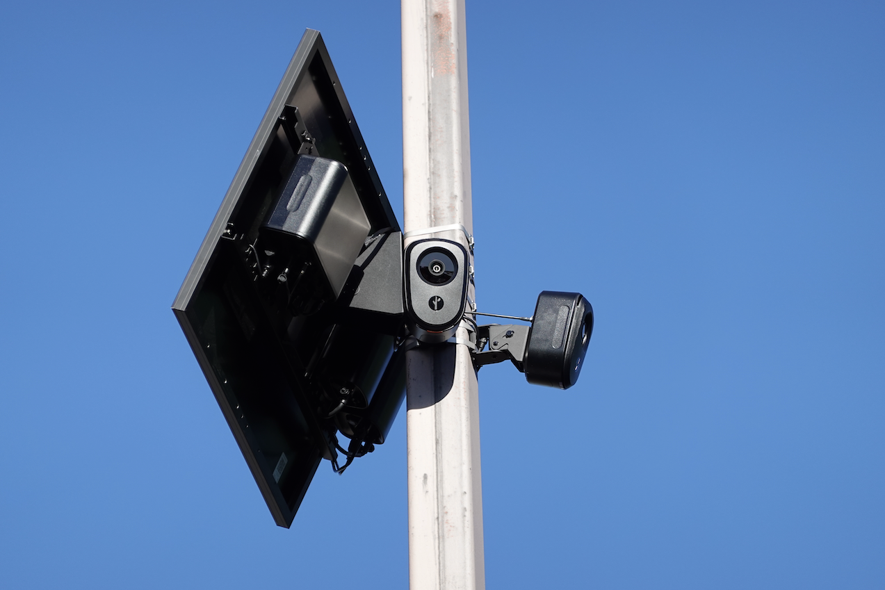 A pair of Flock Safety cameras on a pole, with a solar panel